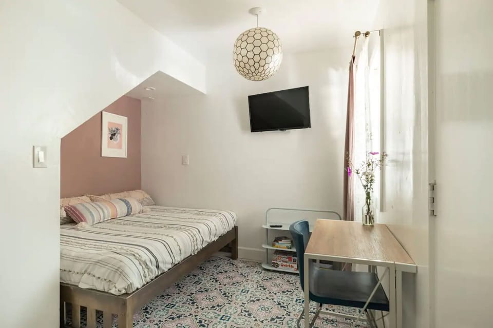 Downstairs entry room with double sized mattress, workspace and tv 