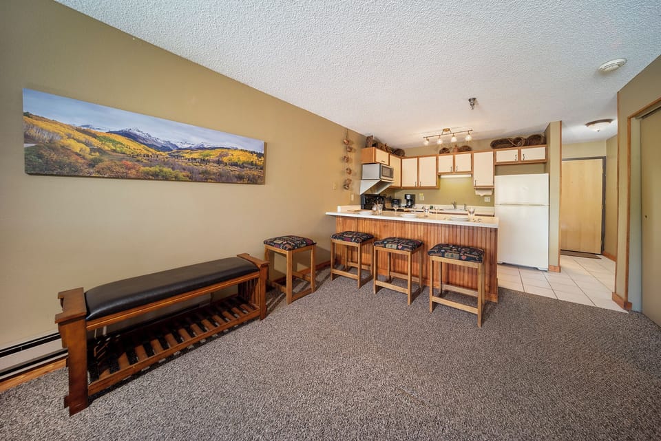 Gather around the kitchen island for morning coffee or evening snacks in this cozy open-plan space with mountain artwork.