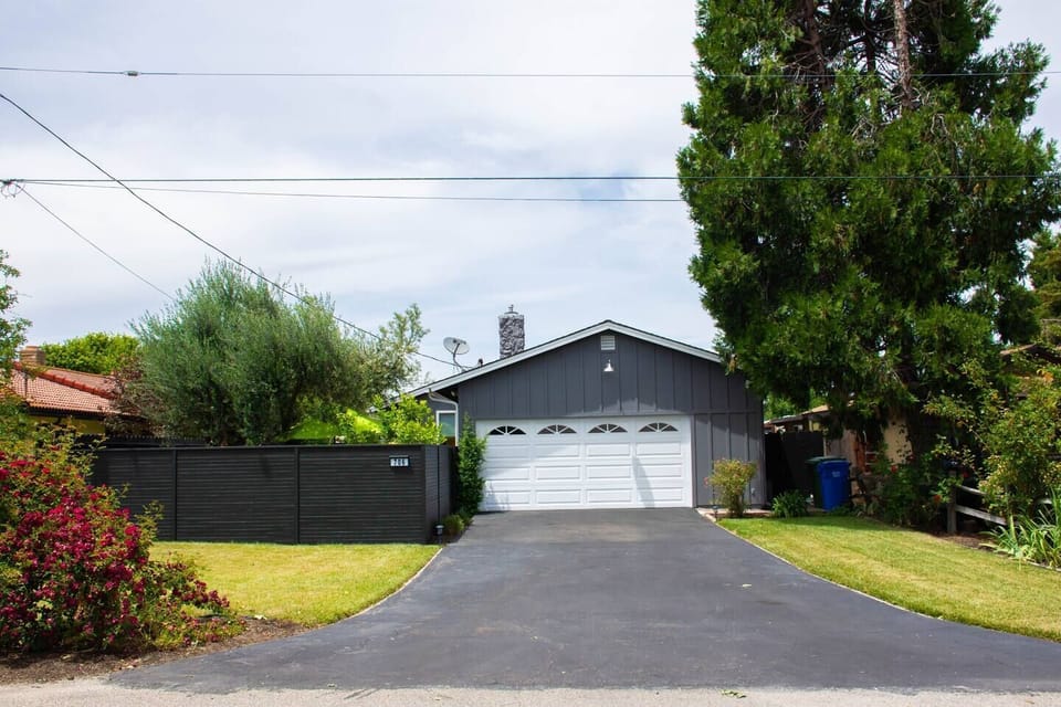 This wide exterior shot showcases the main house's paved driveway and attached two-car garage with a white door.