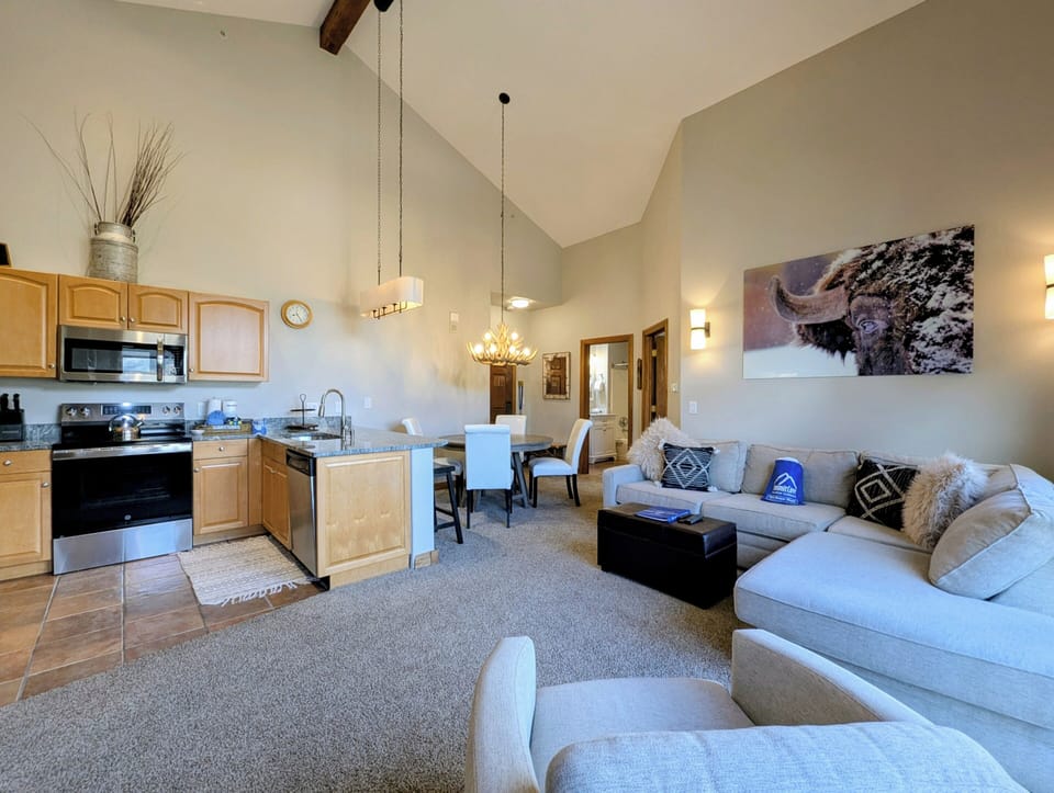 Unwind in this spacious living area where vaulted ceilings and rustic beams create an airy mountain retreat feel.