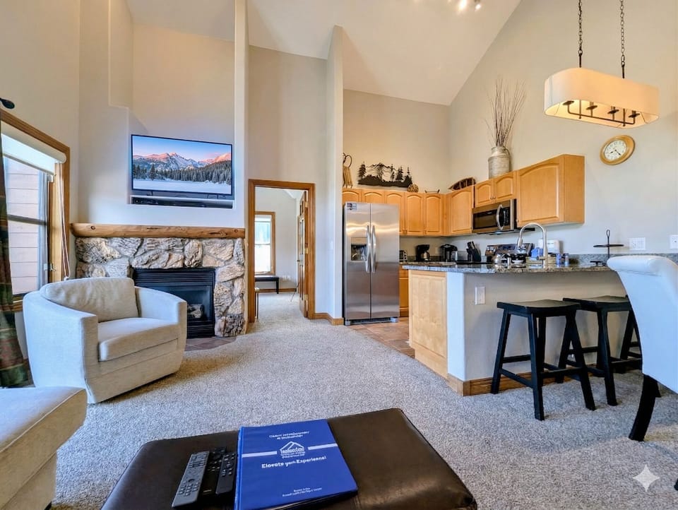 Relax by your stone fireplace while enjoying open-concept living with fully equipped kitchen and mountain views on TV.