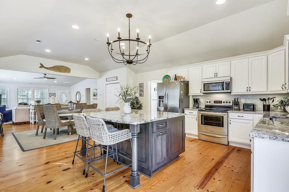 607 Sandstone Court - Renovated Kitchen with Island - This bright, updated kitchen features a large central island with a breakfast bar, crisp white cabinetry, and elegant granite countertops. High-end stainless steel appliances and stylish pendant lighting complete this sophisticated culinary space.