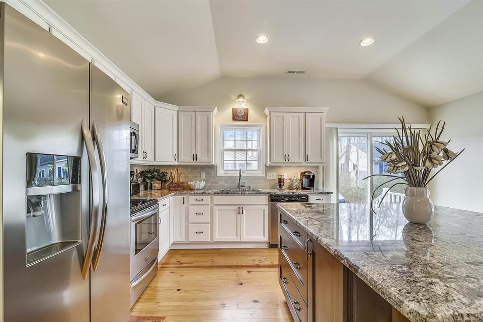 607 Sandstone Court - Gourmet Kitchen Detail - A view showcasing the ample counter space and professional-grade stainless steel refrigerator. The white subway tile backsplash and vaulted ceilings enhance the room’s airy, spacious feel.