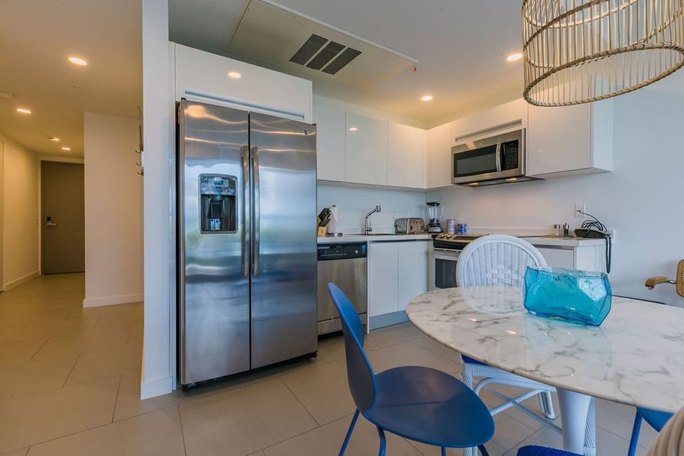 Step into your modern kitchen with sleek stainless appliances, crisp white cabinetry, and a marble dining table—perfect for morning coffee or sharing meals together.