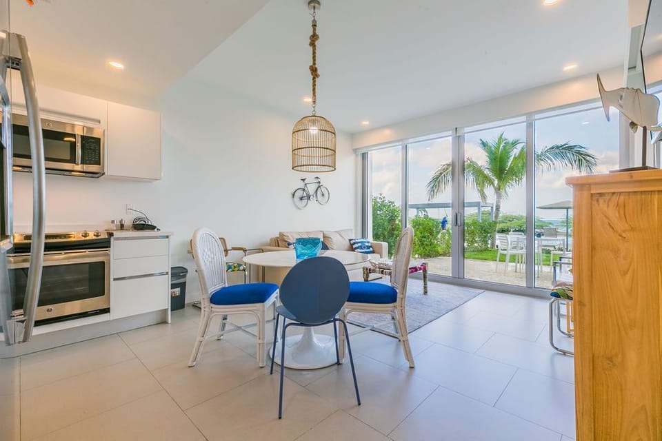 Your bright open living space flows seamlessly from kitchen to lounge, with glass doors framing palm trees and ocean views—perfect for beachside mornings and sunset evenings.