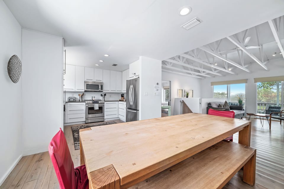 Dining table beside modern kitchen with vaulted ceilings and natural light!