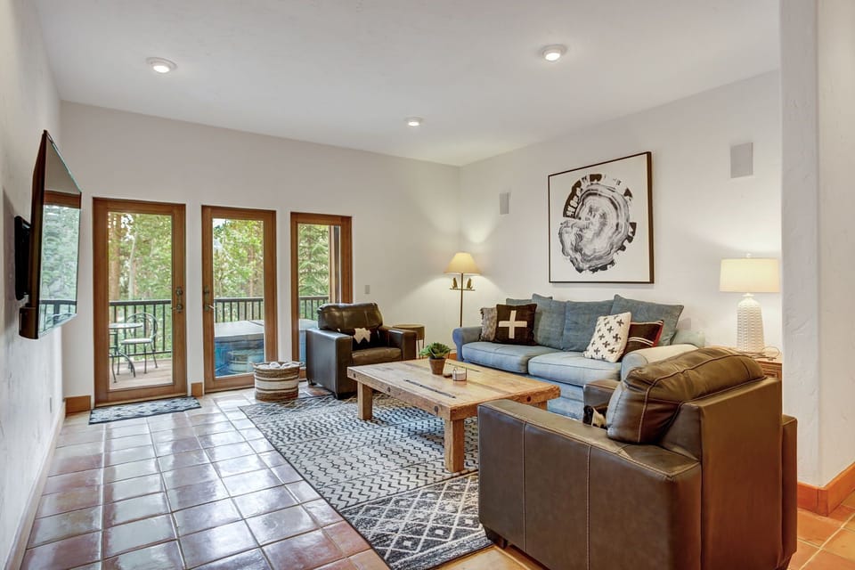 Secondary, lower-level living area with large screen TV, deck, and hot tub.