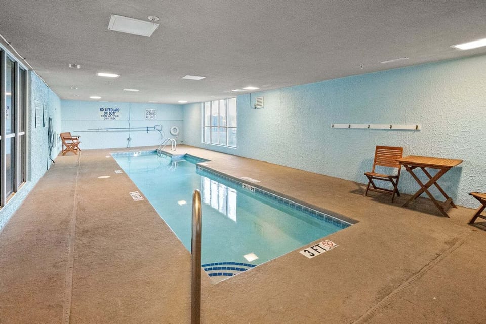 Indoor pool with lounge chairs and tall windows at Ocean Bay Club 604, an Ocean Drive vacation rental