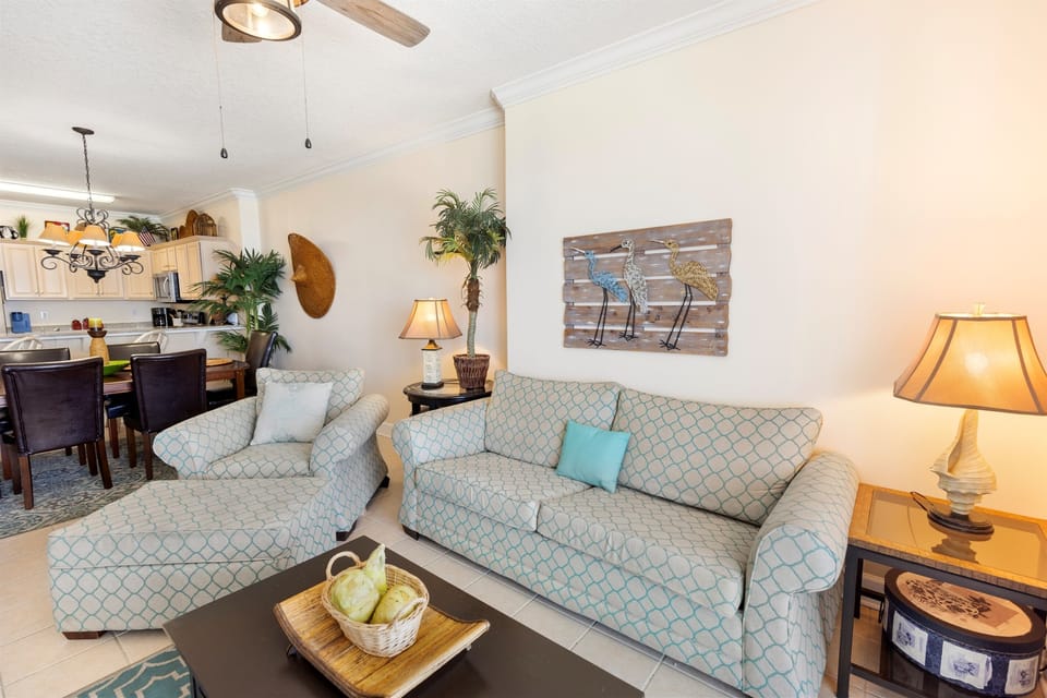 Sink into plush seating where warm coastal light creates your perfect retreat for morning coffee or evening conversations.
