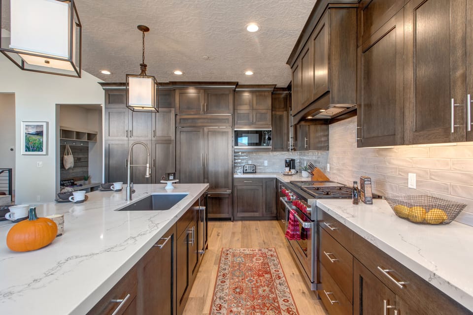 Fully equipped kitchen with stone countertops, stainless steel appliances with stovetop, fridge, and island