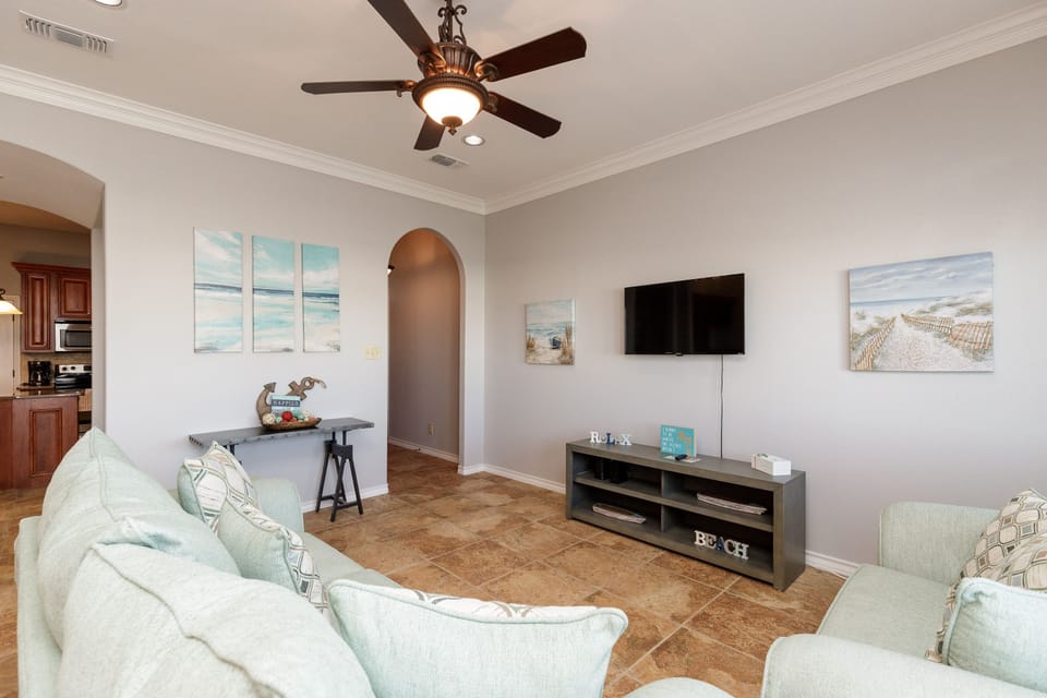 Relax in your bright, airy living room with coastal artwork and comfortable seating, perfect for unwinding after beach adventures.