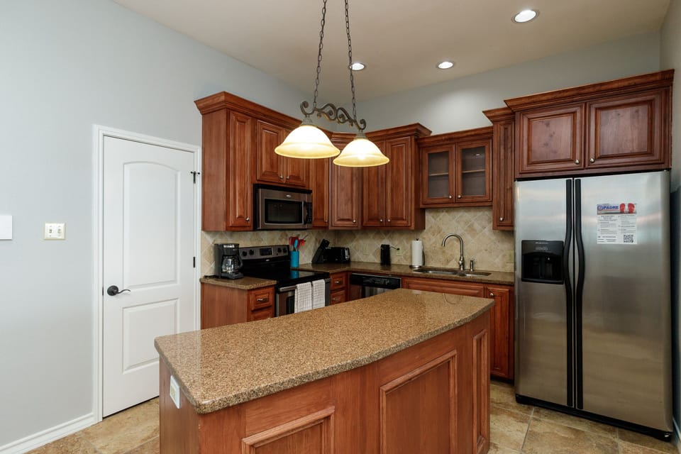 Your fully-equipped kitchen features rich wood cabinets, granite counters, and stainless appliances—perfect for creating memorable meals during your stay.