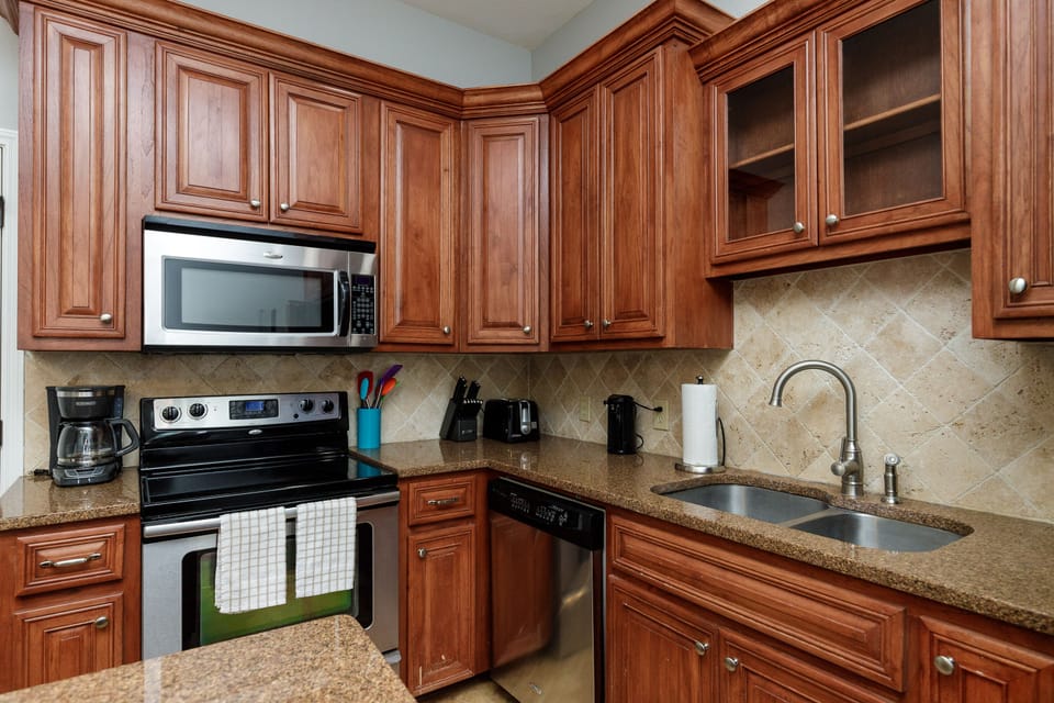 Step into your fully equipped kitchen with rich wood cabinetry, granite counters, and modern appliances for preparing memorable meals.