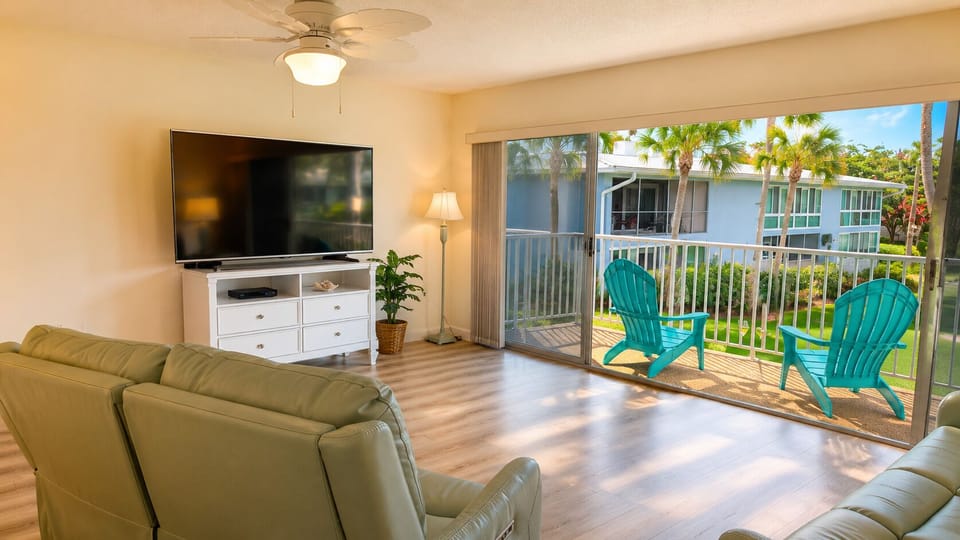 Bright, open living room with balcony access and tropical pool views