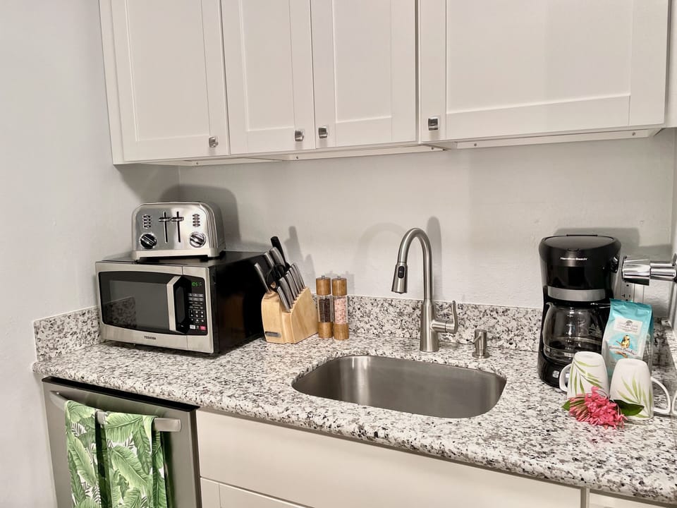 Fully stocked kitchen with dishwasher, microwave, toaster, coffee pot, spices