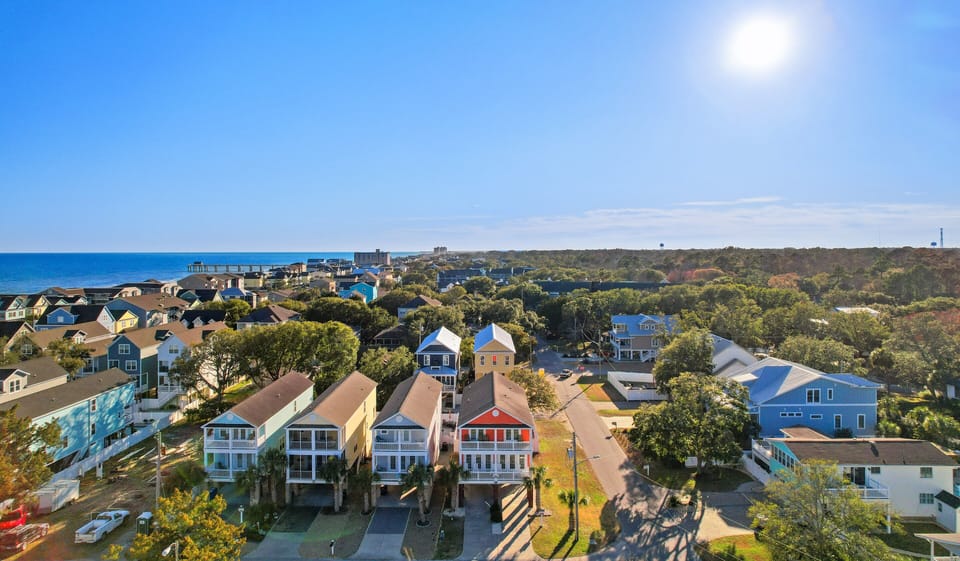 Coastal community with colorful beach houses nestled among trees, just steps from the ocean and nearby attractions.