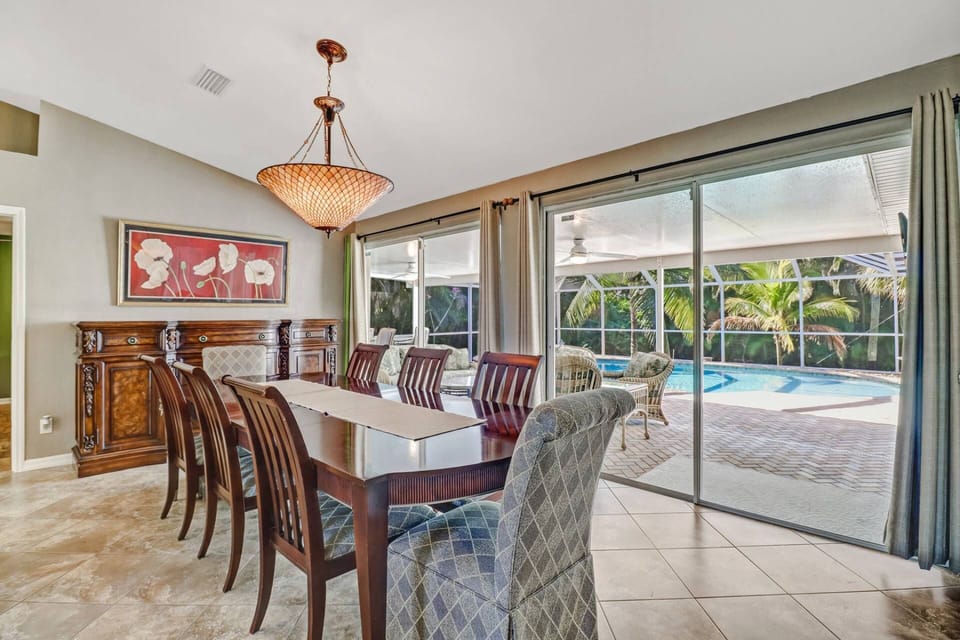 An elegant dining table for 8 enjoys a gorgeous view of the lanai, pool & spa through the large sliding glass doors.
