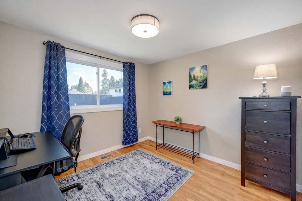 Comfortable room featuring a dedicated workspace, natural light, and a calm setting for productivity.