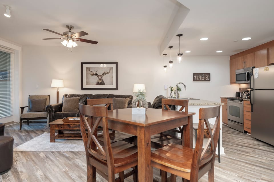 Relax in your open-concept living space with mountain lodge charm, featuring a fully equipped kitchen and cozy seating perfect for group gatherings.