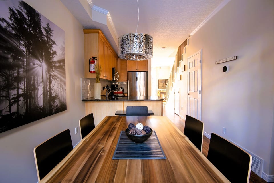 Dining area for 6, acacia live edge table, open kitchen and living room visible in the background.