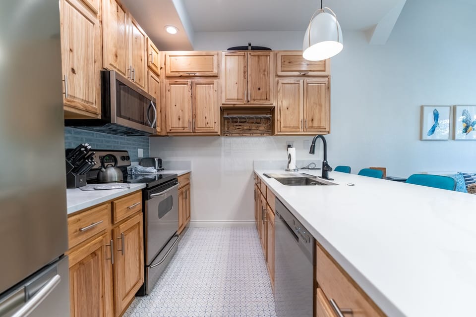 Your fully-equipped kitchen features warm wood cabinetry, modern appliances, and a breakfast bar where you can enjoy morning coffee together.