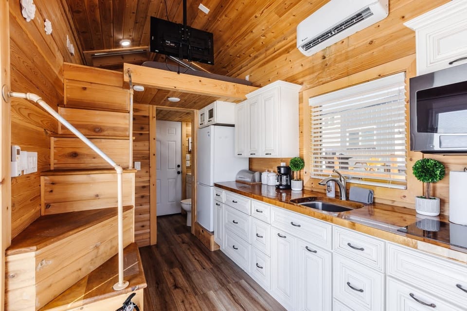 The kitchen is fully equipped with a refrigerator, freezer, microwave, cooktop, and sink with hot/cold water. Enjoy coffee from the coffee maker and ample counter space. Essentials include cookware, dishes, utensils, and plenty of storage cabinets.
