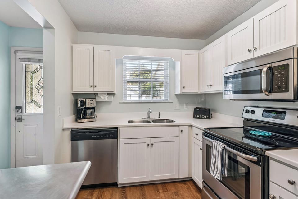 Your bright, fully-equipped kitchen has everything you need to prepare favorite meals, with stainless steel appliances, ample counter space, and a welcoming view of greenery through the window.