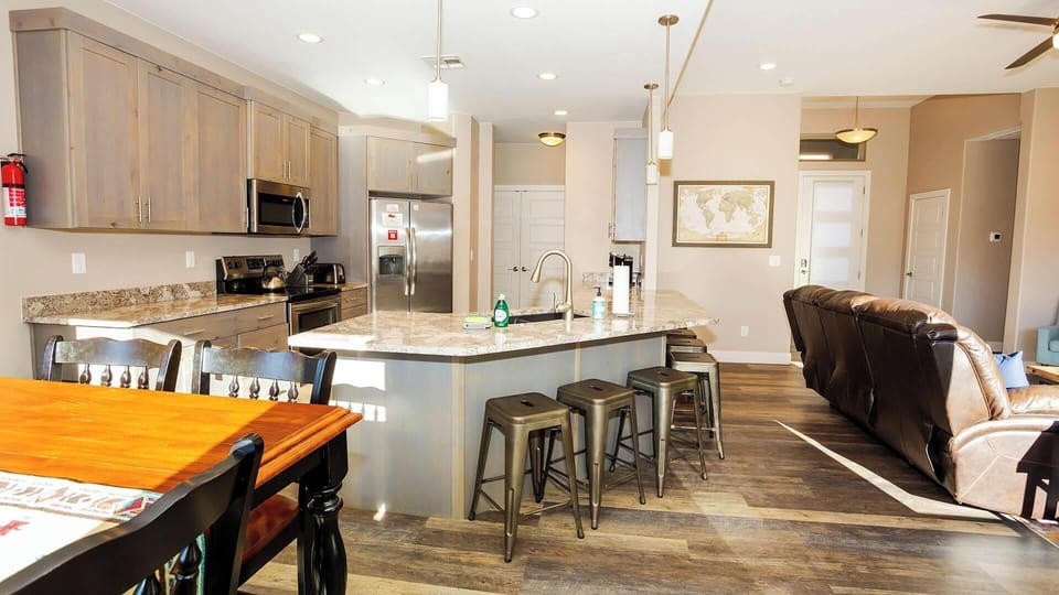 Spacious open-concept kitchen with granite island, stainless appliances & bar seating for four at Maison Sans Souci in Kanab.