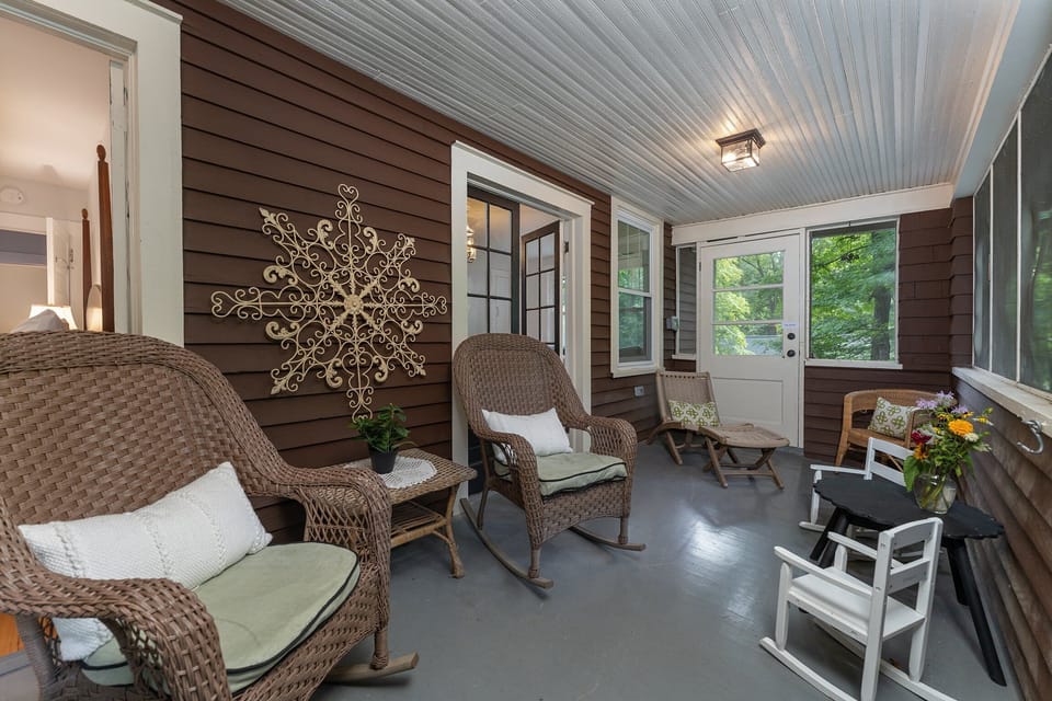Upper-level screened porch with antique daybed and rocking chair seating.