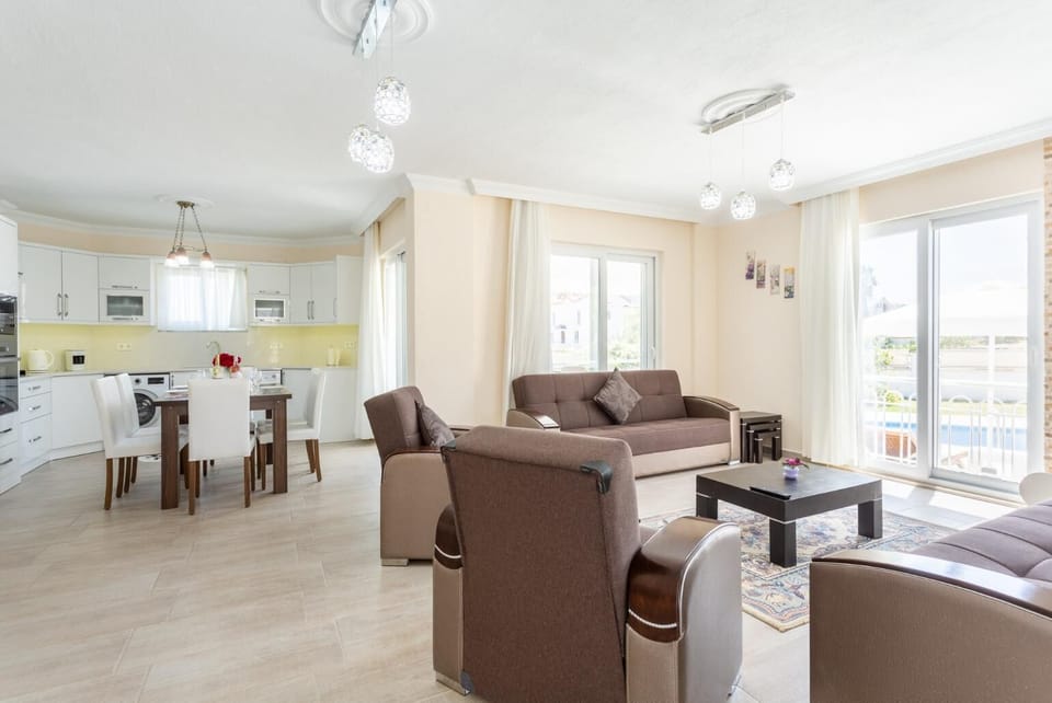 Open-plan living room with sofas, dining area, kitchen, ornamental fireplace, A/C, WiFi internet, satellite TV, and terrace access