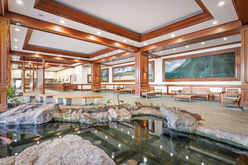 An elegant lobby welcomes you with rich wood accents, a tranquil koi pond, and tropical artwork—setting the tone for your island escape.