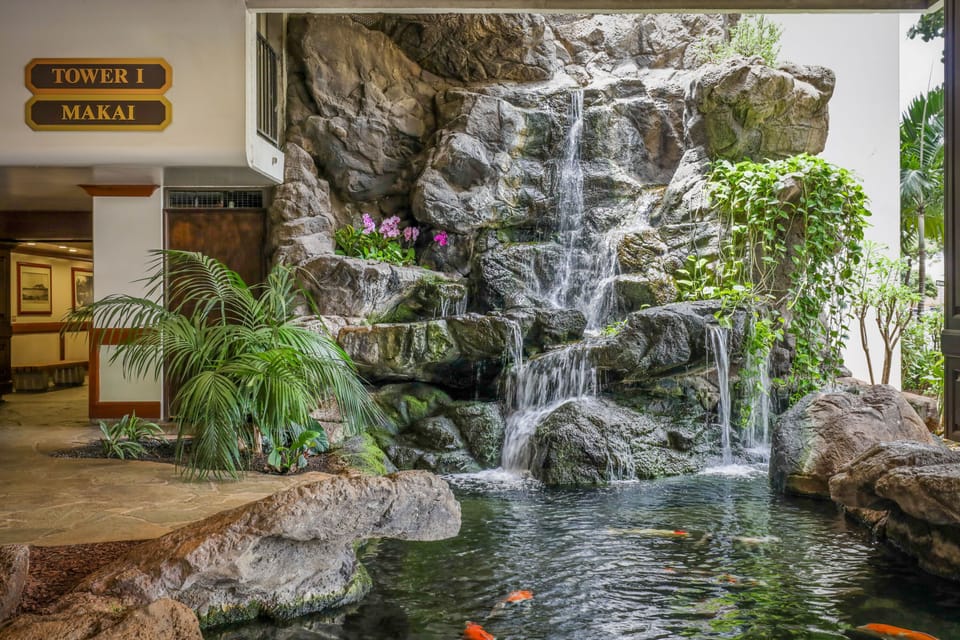 Relax beside a soothing multi-tier waterfall and koi pond in this tranquil indoor courtyard, where lush tropical plants create a peaceful oasis right at your doorstep.