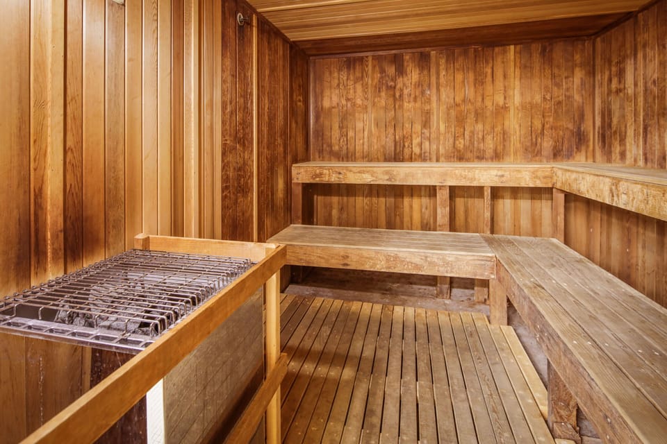Wooden sauna with tiered benches and traditional heated stones invites you to unwind and rejuvenate in soothing warmth and tranquility.