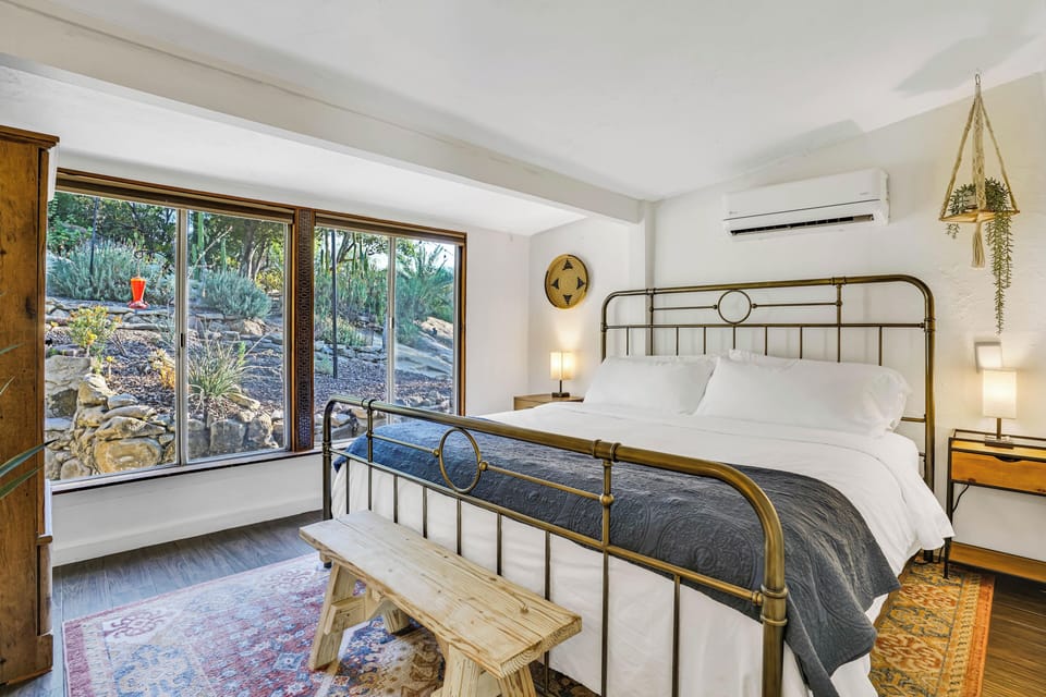 Plush, king-sized bed with large windows and nature views.