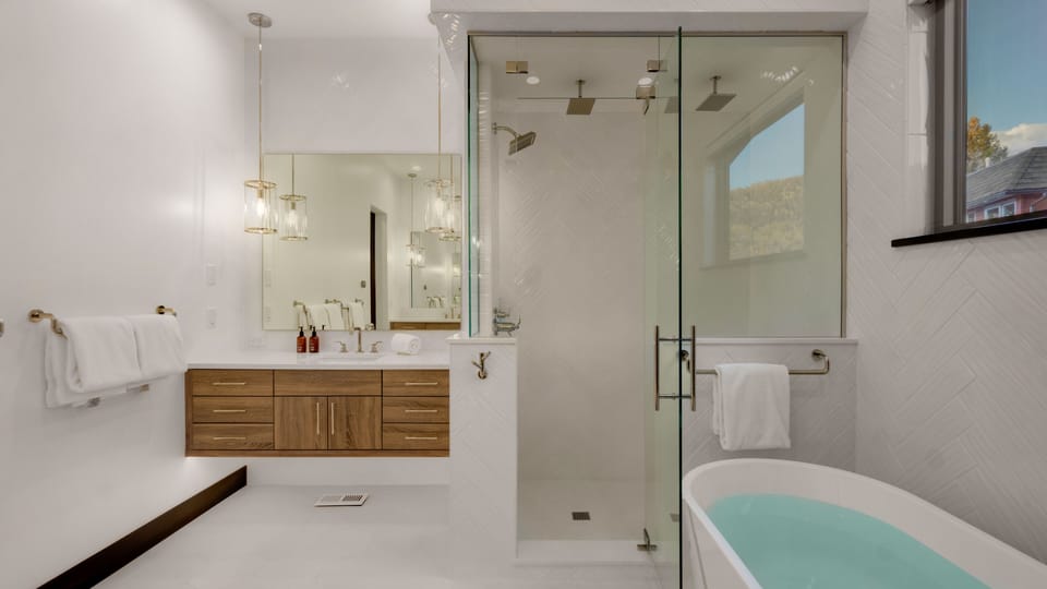 Primary ensuite with separate vanities and 3-head shower