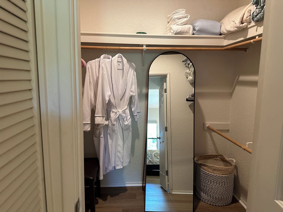 Primary walk in closet with full length mirror and additional linens/pillows