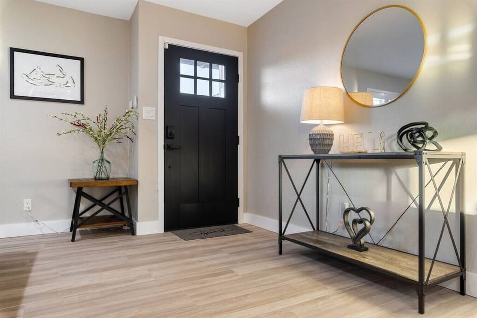 Step into elegance with our stunning foyer featuring a sleek black door and a glamorous mirror.