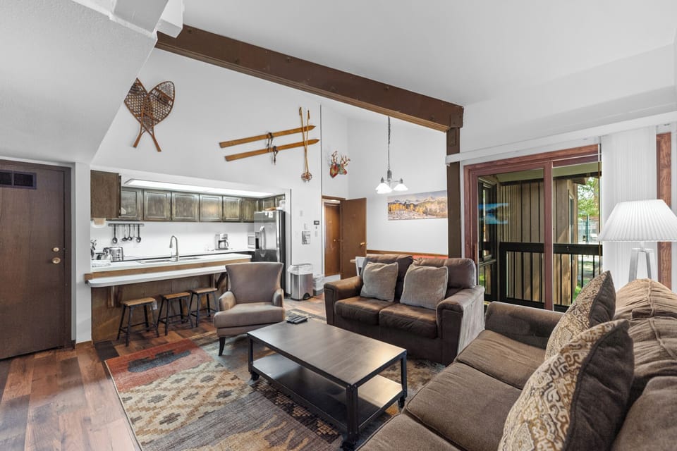 Spacious living area with mounted flat screen TV, wood-burning fireplace, vaulted ceilings, sleeper sofa and access to the private deck.