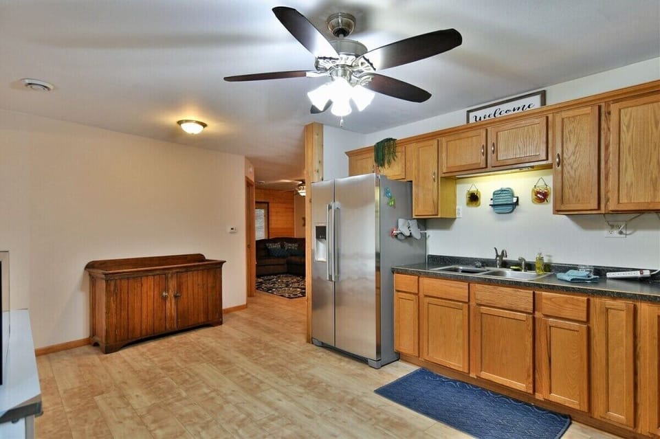 A kitchen view in the Highland Cottage featuring oak cabinets, a stainless steel stove with a tea kettle, a white kitchen island with a coffee station, and a dark countertop.