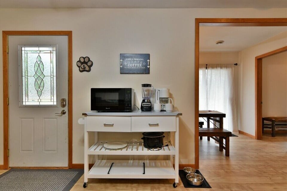 A kitchen view in the Highland Cottage featuring oak cabinets, a stainless steel stove with a tea kettle, a white kitchen island with a coffee station, and a dark countertop.