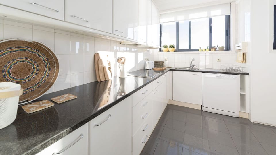 Enjoy preparing your favorite meals in this bright, fully equipped kitchen, featuring ample counter space and all the appliances you need for a comfortable stay. The large window floods the area with natural light, making cooking a pleasure.