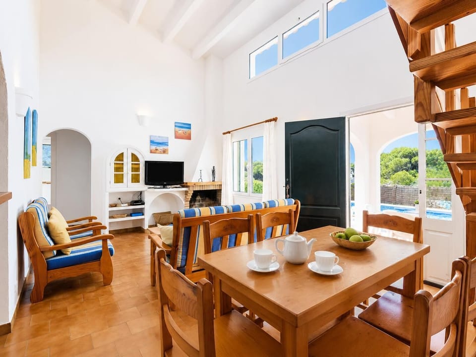 Open-plan living room with sofas, dining area, kitchen, ornamental fireplace, A/C, WiFi internet, and satellite TV