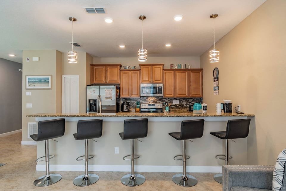 Enjoy this stylish kitchen with warm wood cabinetry and sleek granite countertops that inspire culinary creativity. The modern bar stools and chic pendant lights offer a delightful casual dining experience in an inviting.