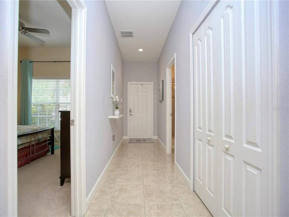 Enter a bright hallway with soft gray walls guiding you to cozy rooms. The elegant tile flooring adds sophistication, and the natural light creates a warm, inviting atmosphere for your stay.