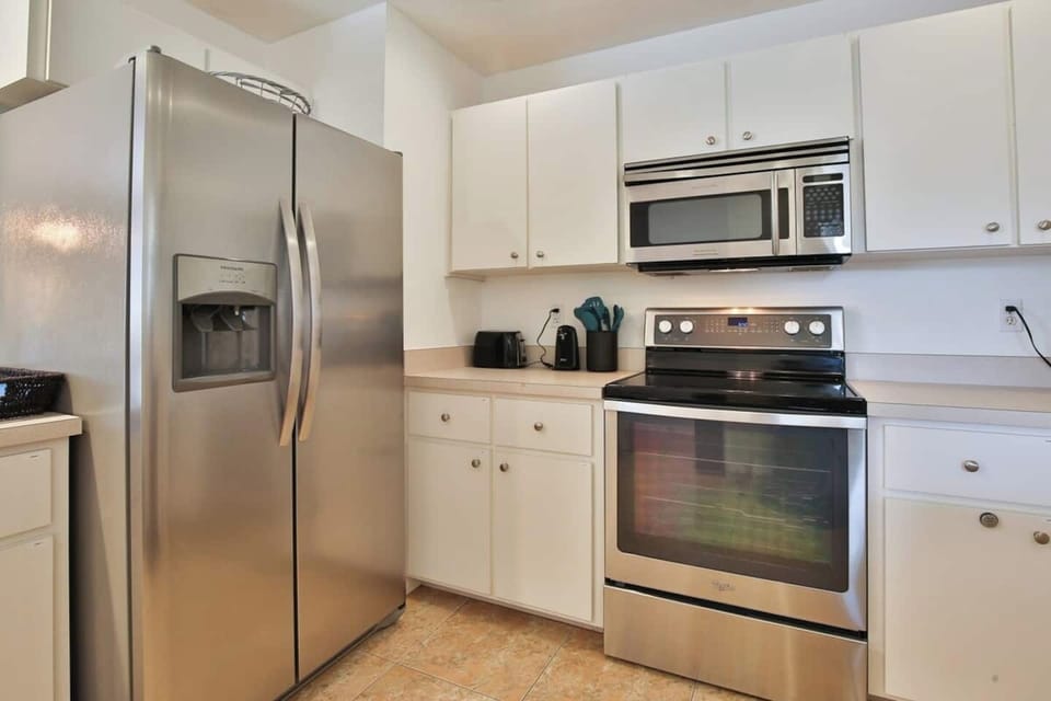 Spacious kitchen with stainless steel appliances and plenty of cooking and baking utensils and tools