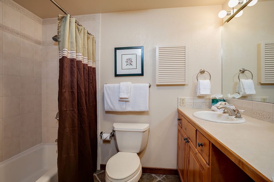 Your private bathroom offers a full tub-shower combo, fresh towels, and wood vanity with ample counter space for your comfort and convenience.