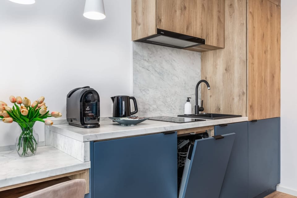 A compact kitchen corner with a modern kettle, wooden accents, and elegant navy cabinets.
