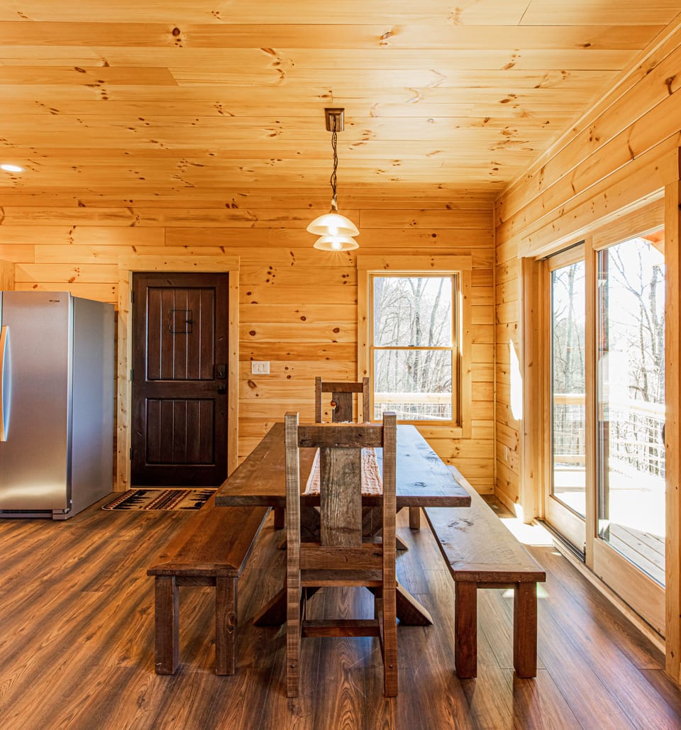 Dining room with sliding doors leading out to deck with gas grill and table.