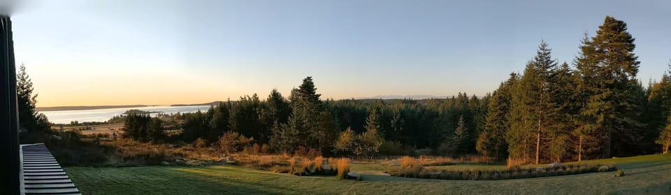 Salish Sea and Olympic Mountain views across the meadow and forest at the Inn