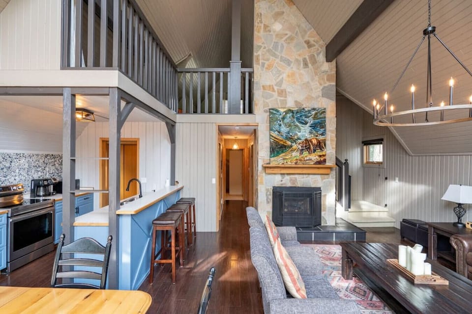 Living room with a gas fireplace, cozy seating & huge windows.